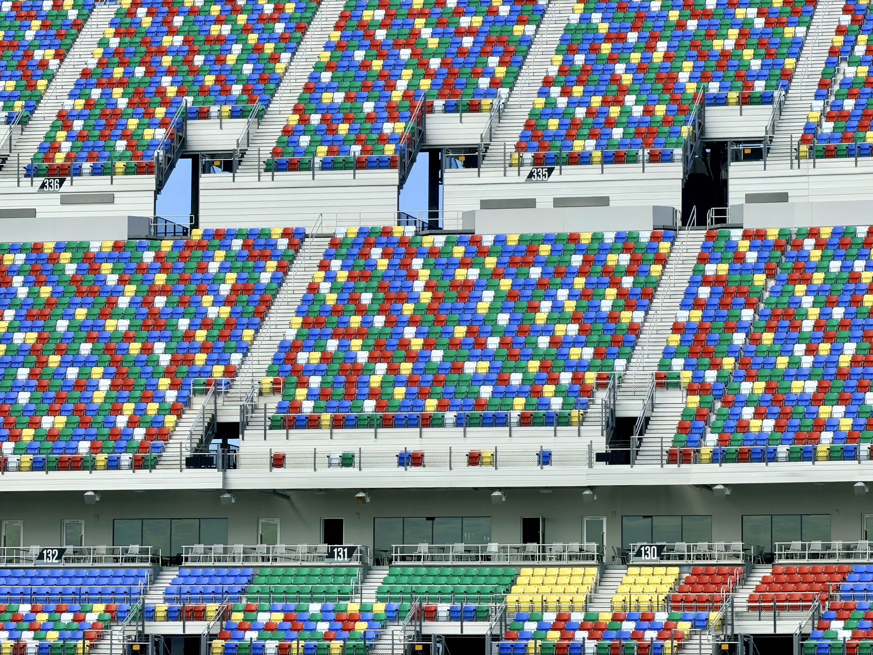 A faraway shot of the empty grandstands at Daytona International Speedway, with their random primary colors on display